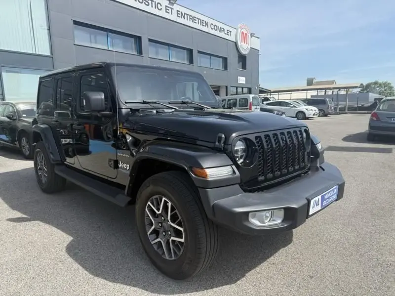 Jeep Wrangler Unlimited noir en 3/4 avant droit, avec calandre iconique à sept fentes et feux ronds visibles.
