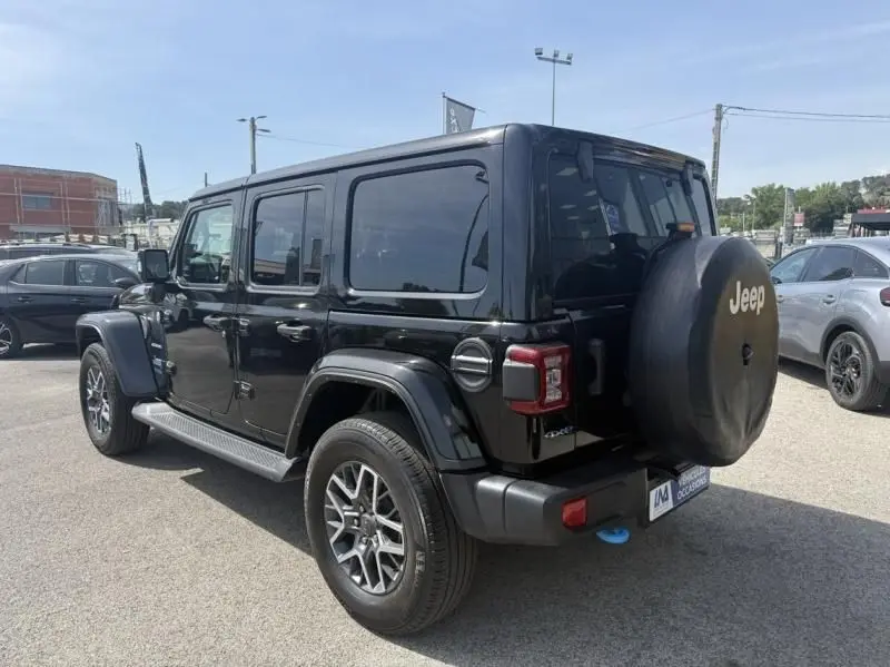 Jeep Wrangler Unlimited 2022 noir en 3/4 arrière droit, avec roue de secours couverte et jantes alliage visibles.