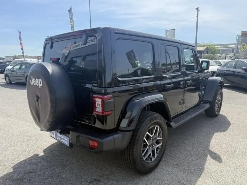 Jeep Wrangler Unlimited 2022 noir vu en 3/4 arrière droit, avec roue de secours sur hayon et jantes alliage.