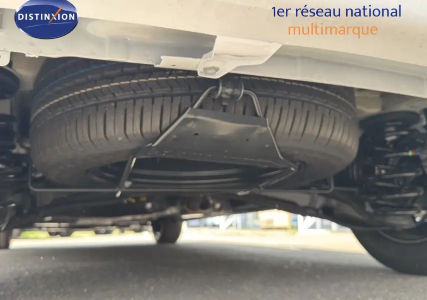 Vue en contre-plongée sous un Citroën Jumpy blanc Kaolin, montrant la roue de secours et la suspension arrière.