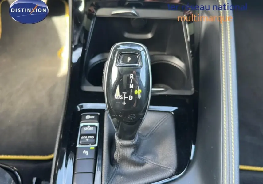 Le levier de vitesses automatique noir de la BMW X2 M Sport X 2018, avec console et surpiqûres jaunes visibles.