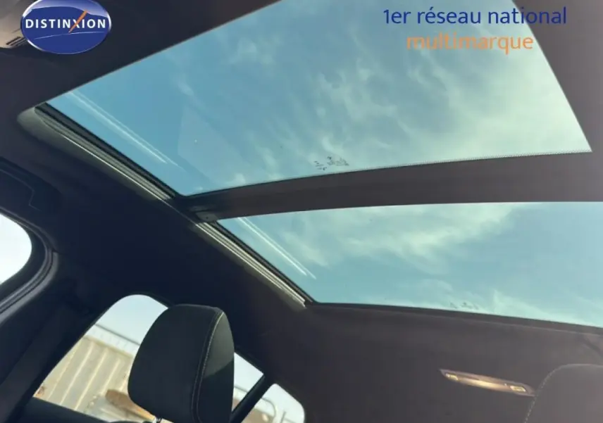 Toit ouvrant panoramique vu de l'intérieur d'une BMW X2 blanc, avec ciel visible à travers le verre.