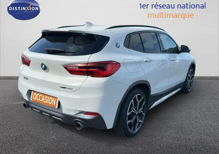 Vue 3/4 arrière droite d’un BMW X2 blanc avec jantes alliage 19 pouces et double sortie d’échappement.