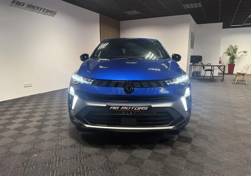 Vue avant d'une Renault Symbioz bleu Iron avec éclairage LED et calandre noire dans un showroom.
