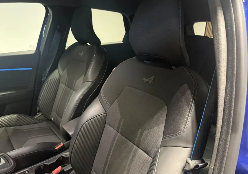 Vue intérieure des sièges avant noirs avec logo Alpine sur une Renault Symbioz bleu, soulignant les finitions sportives.