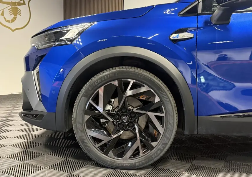 Gros plan sur la roue avant gauche et l’aile d’une Renault SYMBIOZ bleu Iron avec badge Esprit Alpine visible.