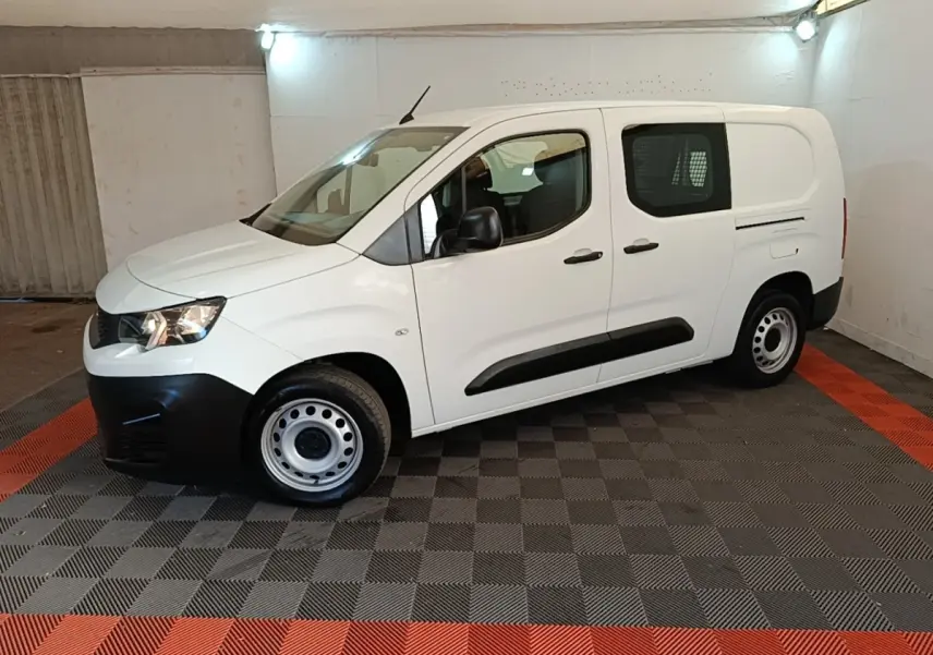 Peugeot Partner blanc en vue de profil côté gauche, avec cloison grillagée visible à l'arrière.