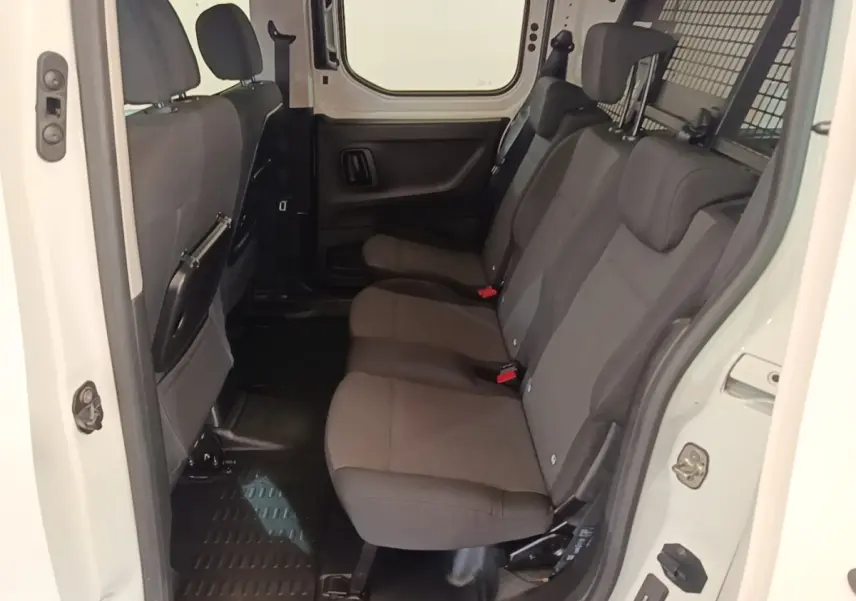Vue intérieure côté droit sur la banquette arrière grise du Peugeot Partner blanc avec cloison grillagée pleine.