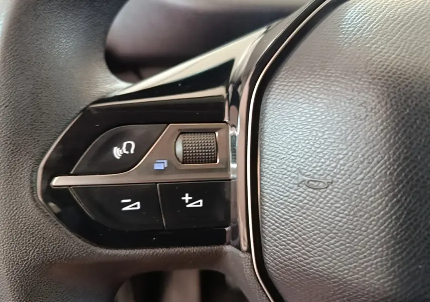 Gros plan sur les commandes gauche du volant noir du Peugeot Partner blanc, version BlueHDi 100 S&S Long Cabine App 2020.