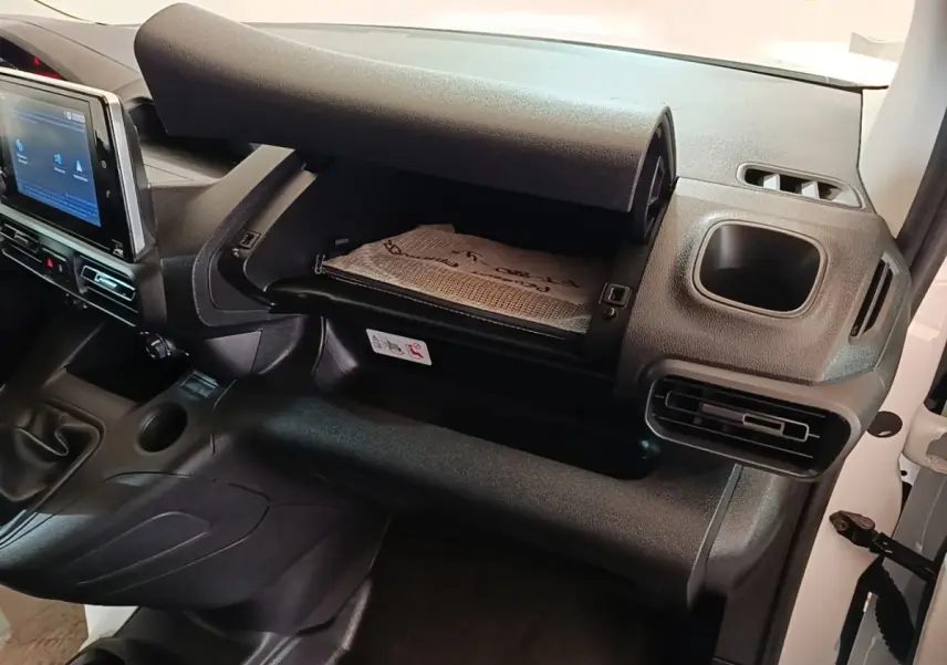 Intérieur du Peugeot Partner 2020, vue côté passager sur la boîte à gants ouverte et la console centrale noire.