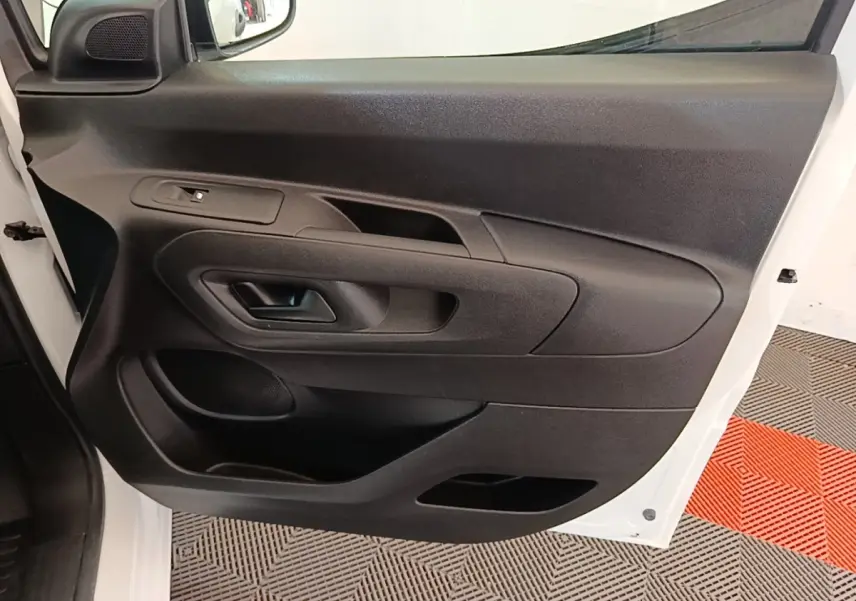 Vue rapprochée de la porte avant gauche noire avec poignée et commande de vitre du Peugeot Partner blanc 2020.