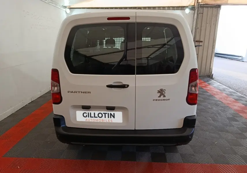 Vue arrière d'un Peugeot Partner blanc 2020 avec portes battantes et logo visible en garage.