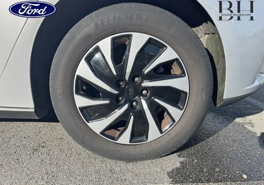 Gros plan sur la roue avant droite avec jante bicolore noir et gris d'une Ford Focus gris lunaire métallisé.