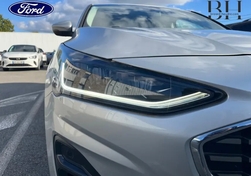 Gros plan sur le phare avant droit de la Ford Focus 2023 gris lunaire métallisé avec calandre chromée visible.