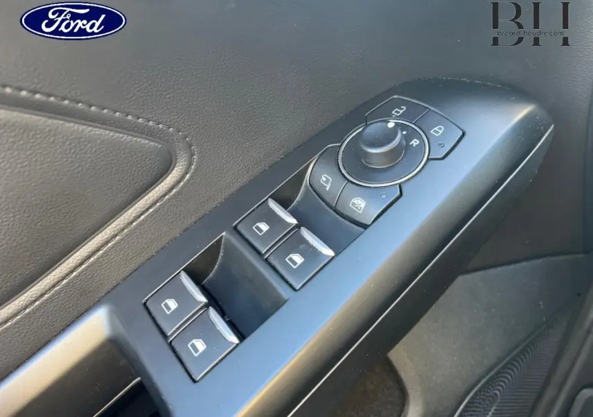 Gros plan sur la commande des vitres et rétroviseurs côté conducteur de la Ford Focus gris lunaire 2023.