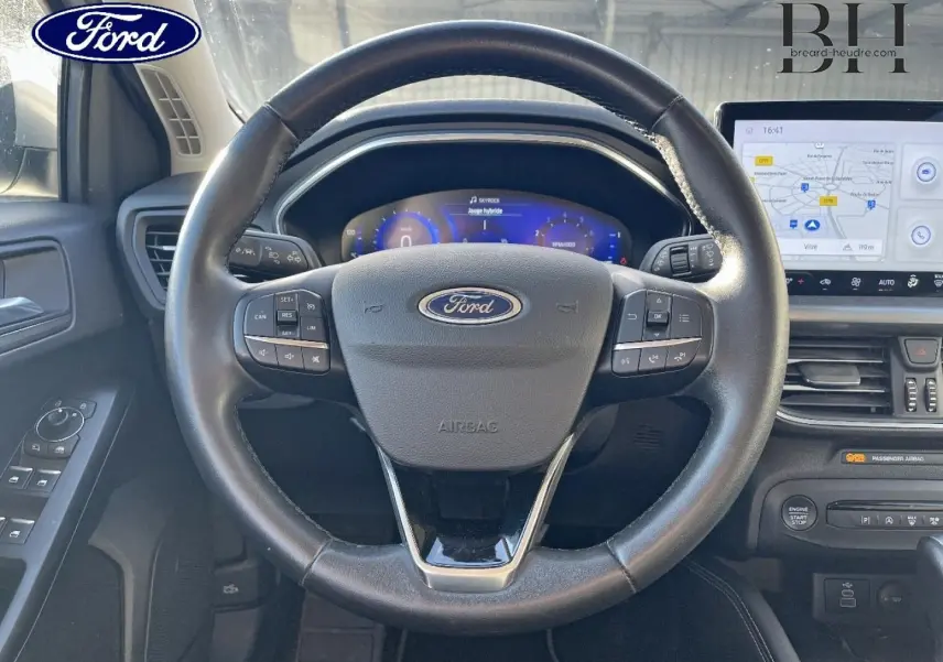 Vue intérieure centrée sur le volant cuir multifonction de la Ford Focus 2023 avec tableau de bord numérique et écran tactile.