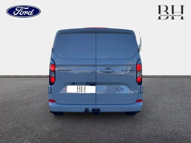 Vue arrière d'un Ford Transit Custom Fourgon gris Matter Spéciale avec double portes et crochet d'attelage visible.
