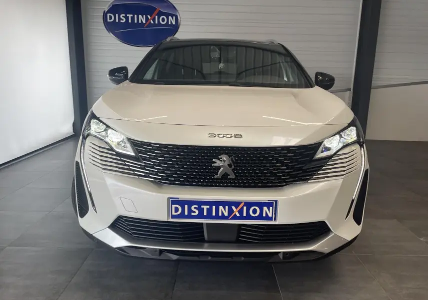 Vue avant d'un Peugeot 3008 blanc nacré avec calandre noire et logo lion chromé, en intérieur showroom.