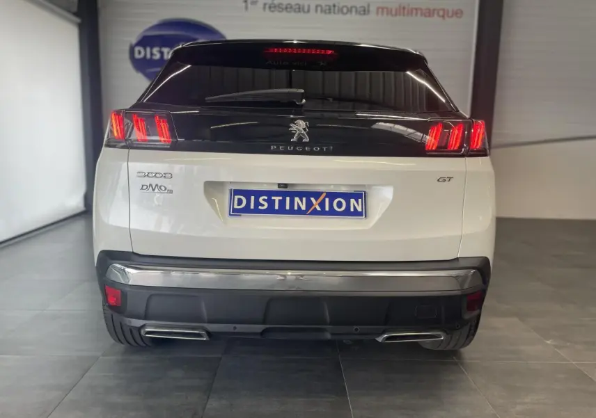 Vue arrière d’un Peugeot 3008 GT blanc nacré avec feux LED et double sortie d’échappement chromée.
