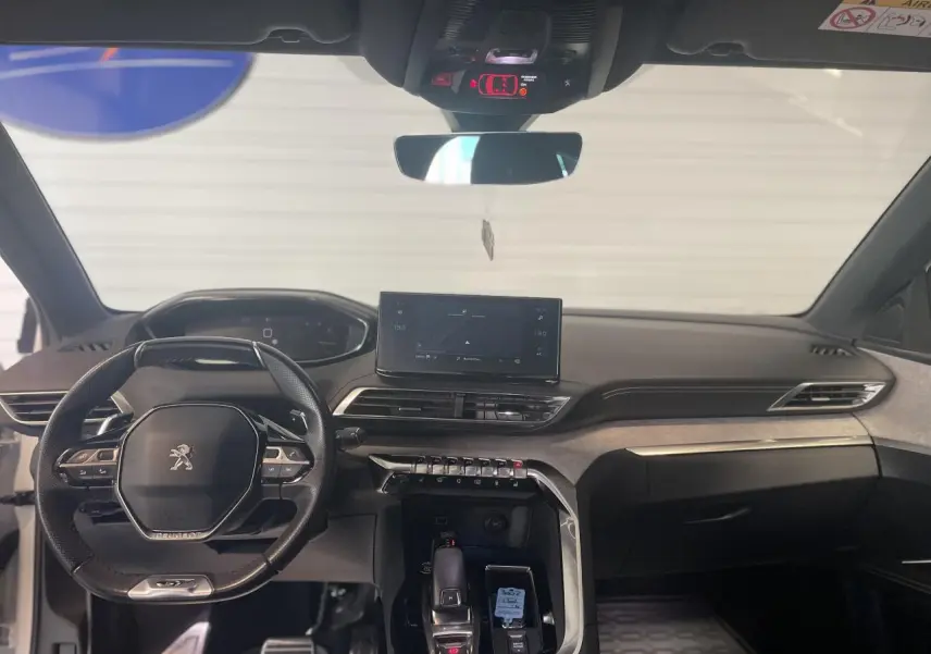 Vue intérieure avant du Peugeot 3008 GT 2022, tableau de bord et volant compact noir avec inserts chromés.