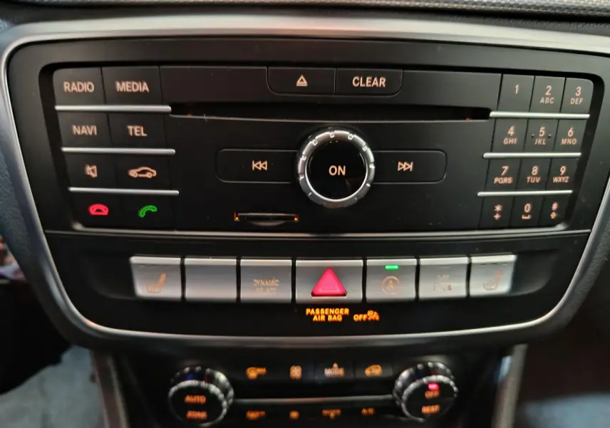 Gros plan sur la console centrale noire du Mercedes GLA 200 d Business Executive gris clair, avec commandes multimédia et climatisation.