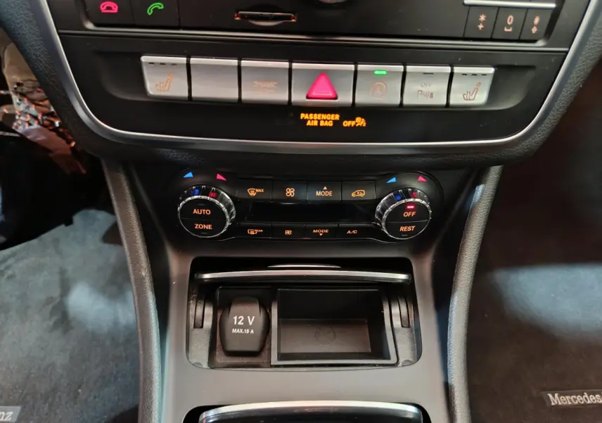 Vue rapprochée de la console centrale du Mercedes GLA 200 d gris clair, avec commandes climatisation et prise 12V visibles.