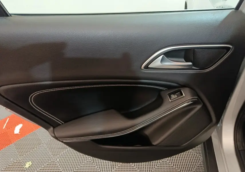Vue intérieure du panneau de porte avant droit noir avec surpiqûres blanches d'une Mercedes GLA 200 d gris clair 2018.