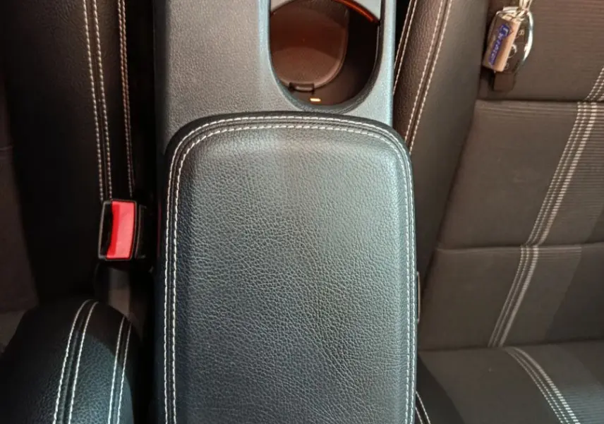 Vue plongeante sur la console centrale cuir noir avec surpiqûres blanches et porte-gobelets du Mercedes GLA 200 d gris clair.