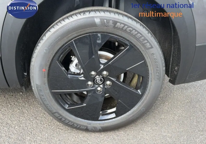 Gros plan sur la roue avant gauche du Citroën C5 Aircross Hybrid gris platinium avec jante noire brillante.