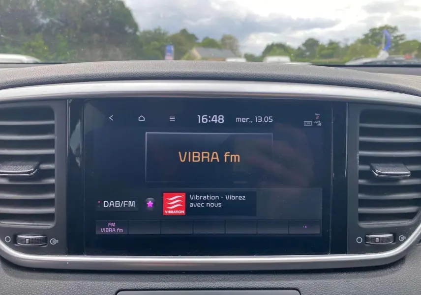 Écran tactile 8 pouces du Kia Sportage gris foncé, affichant la radio VIBRA fm en intérieur.