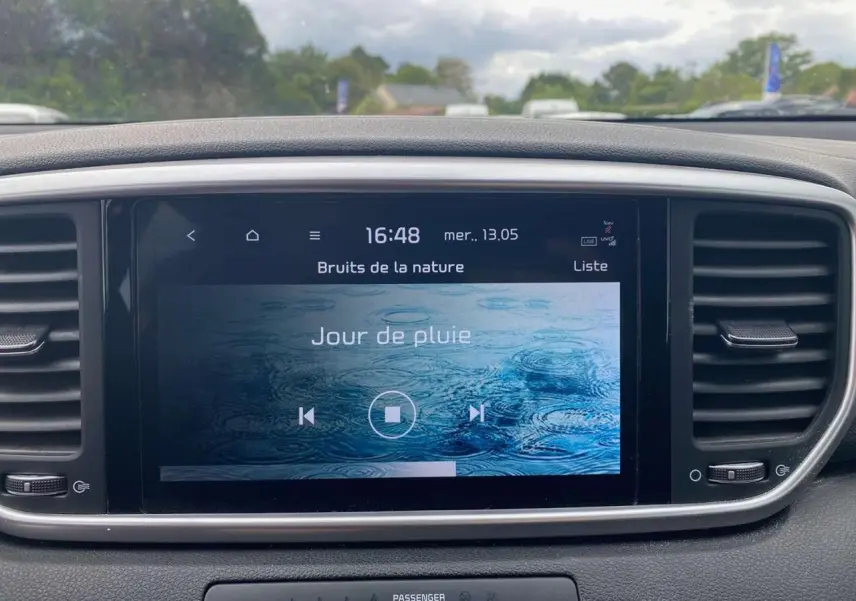 Écran tactile central 8 pouces du Kia Sportage 2021, affichant une ambiance sonore "Jour de pluie" dans un intérieur noir.