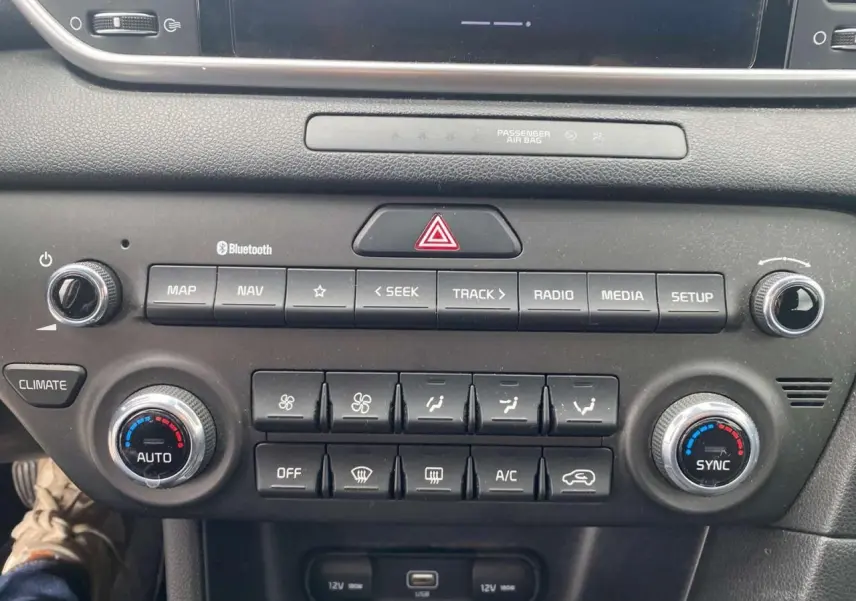 Tableau de bord du Kia Sportage 2021, vue frontale centrée sur la console avec commandes climatisation et multimédia.