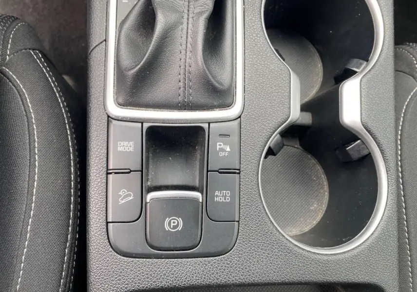 Vue rapprochée de la console centrale du Kia Sportage 2021, montrant le levier de vitesse cuir et les commandes de frein électrique.