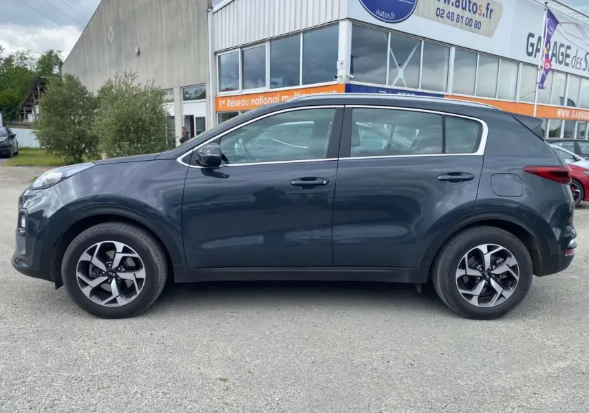 Vue de profil côté gauche d'un KIA Sportage gris foncé 2021 avec jantes alliage noires Black Edition.