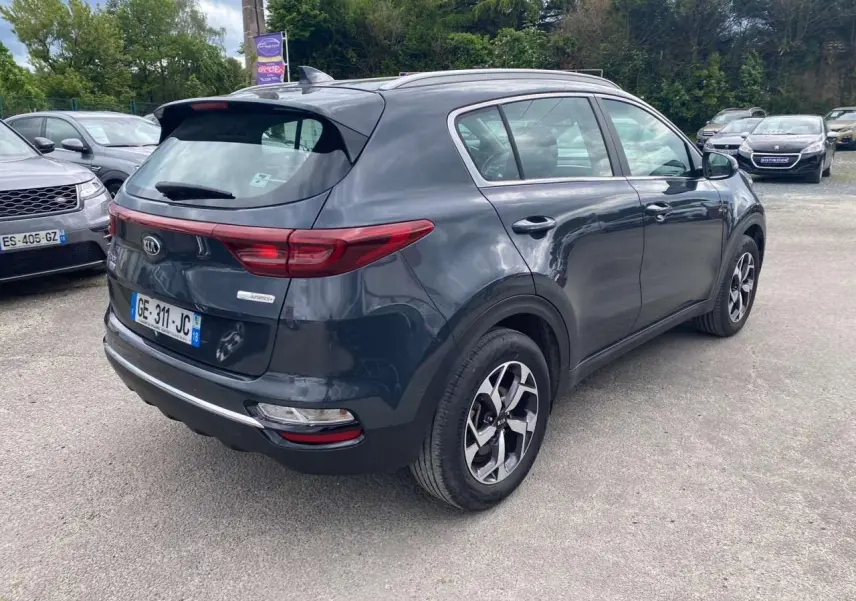 Vue 3/4 arrière droite d’un KIA SPORTAGE gris foncé métallisé avec jantes alliage noires Black Edition.