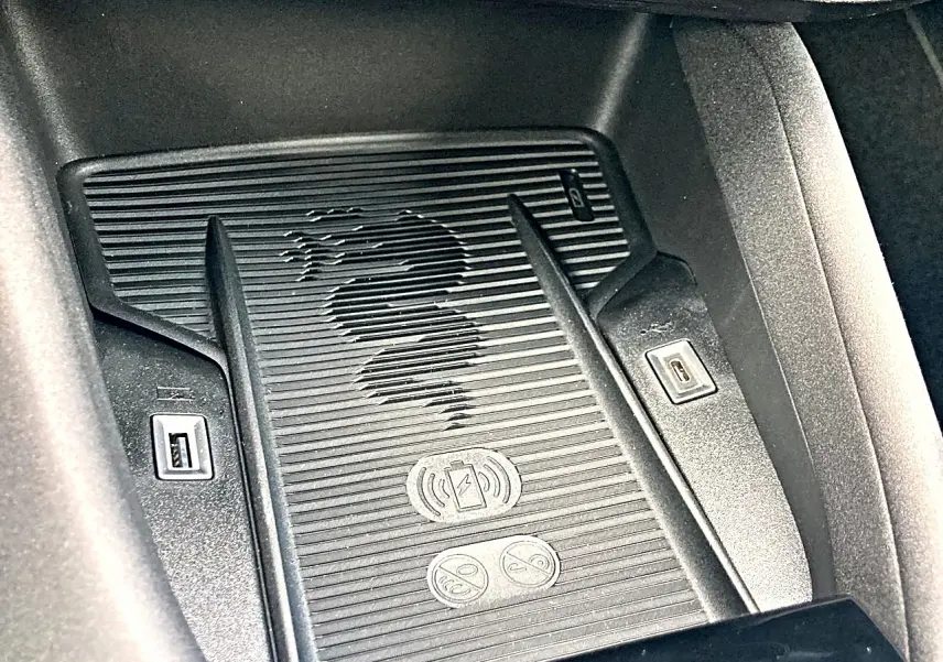Gros plan sur le chargeur à induction avec logo Alfa Romeo et ports USB dans l’habitacle du Junior gris.