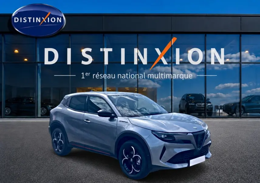 Vue 3/4 avant droite d'une Alfa Romeo Junior gris métallisé avec jantes en alliage devant une vitrine Distinxion.