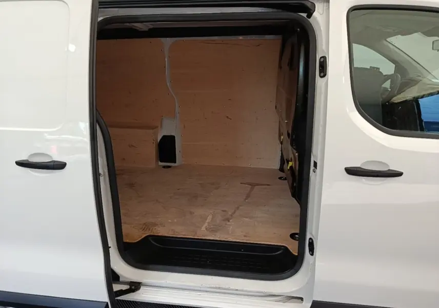 Vue latérale gauche d’un Peugeot Expert Fourgon blanc avec porte coulissante ouverte dévoilant l’espace de chargement en bois.