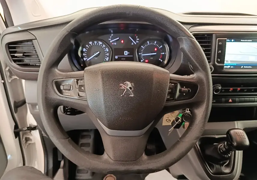 Vue intérieure centrée sur le volant noir Peugeot avec tableau de bord et levier de vitesses manuel visible.