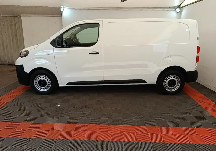 Profil côté gauche d’un fourgon Peugeot Expert blanc, version Standard Asphalt, sur sol à damier noir et rouge.