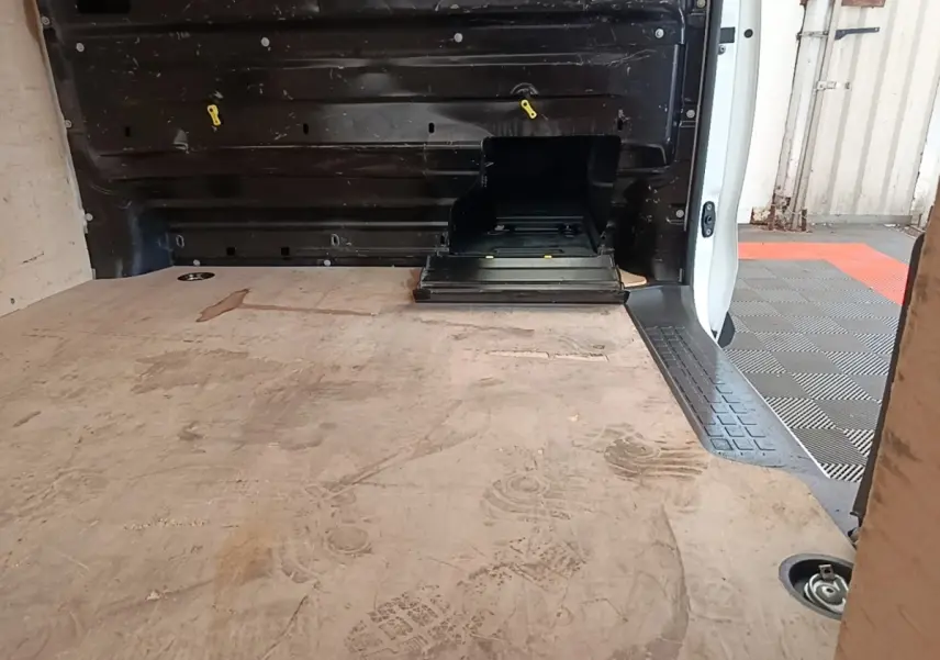 Vue intérieure du coffre arrière du Peugeot Expert Fourgon blanc, montrant le plancher en bois et la cloison pleine noire.