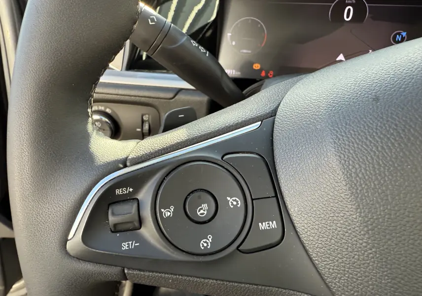 Gros plan sur les commandes du volant côté gauche de l'Opel Grandland gris Artense avec toit noir, modèle 2024.
