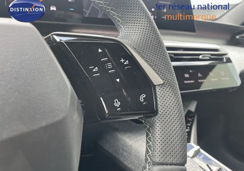 Gros plan sur le volant en cuir perforé avec commandes intégrées du Peugeot 5008 Hybrid 2025, intérieur moderne noir.