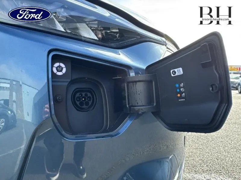 Prise de recharge ouverte côté avant gauche du Ford Transit Custom Fourgon bleu azur métallisé 2025.