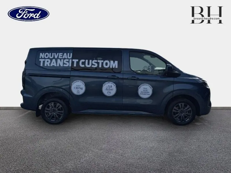 Profil droit du Ford Transit Custom bleu azur métallisé avec marquages blancs publicitaires sur la carrosserie.
