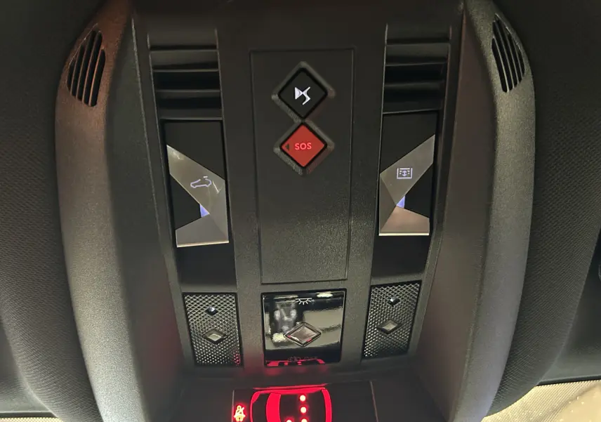 Vue rapprochée du panneau de commandes au plafond du DS7 2024 en noir, avec boutons SOS et ouverture hayon éclairés.