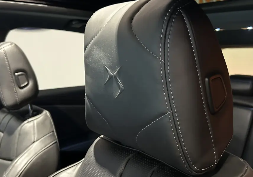 Gros plan sur l'appui-tête en cuir noir embossé du logo DS à l'intérieur du DS7 2024 avec toit ouvrant.