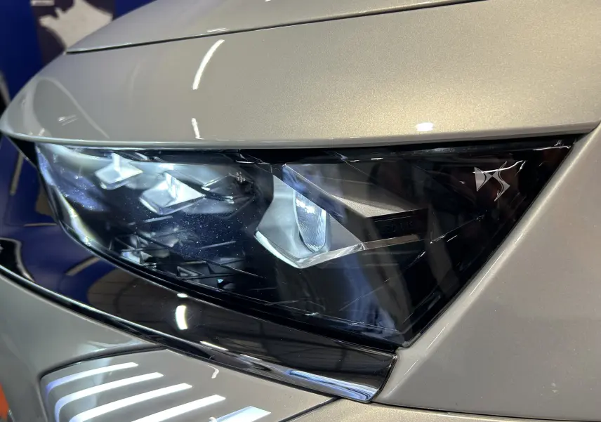 Gros plan sur le phare avant droit du DS7 2024 en couleur Chrystal pearl, mettant en valeur son design LED distinctif.