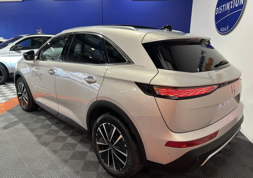 DS7 BlueHDI 130 en Chrystal pearl, vue 3/4 arrière droit, hayon électrique et toit ouvrant visibles en showroom.