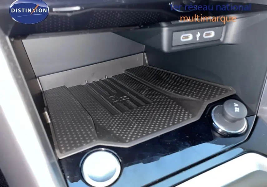 Vue rapprochée de la console centrale du Volkswagen T-Roc noir, mettant en valeur le chargeur sans fil et les ports USB.